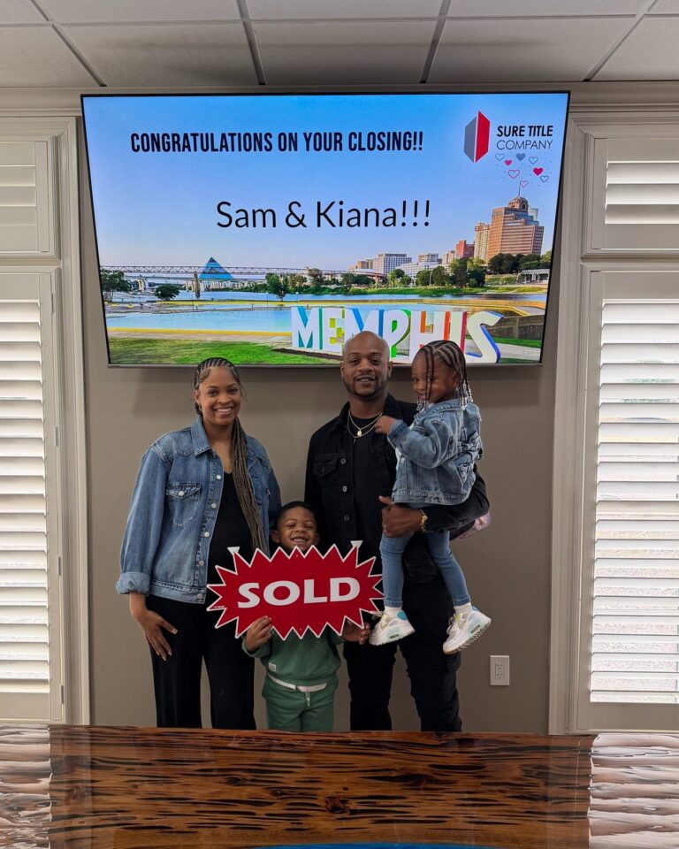 Family celebrating their home purchase with a SOLD sign at Sure Title Company in Memphis
